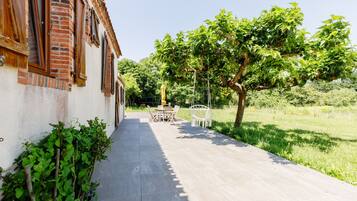 A pathway leading to a building with a brick facade and a garden area with a table and chairs.