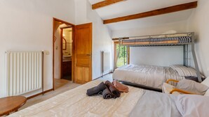 A bedroom with a bunk bed, a wooden ceiling, a radiator, and a door leading to a bathroom. - La Chaumière de Jeannot - Maison avec jardin pour 8 (La Chapelle-Hermier)