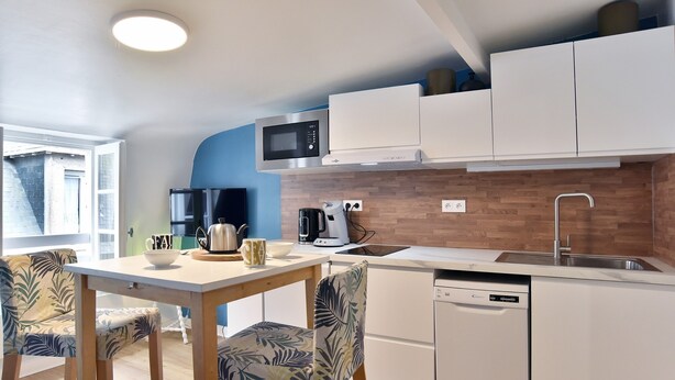 A modern kitchen with white cabinets, a microwave, a coffee maker, and a dishwasher. - Le Cocon des Remparts - Au coeur de l'intramuros (Saint-Malo)
