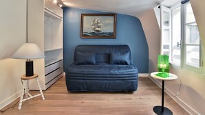 A bedroom with a bed, a painting, a lamp, and a window. - Le Cocon des Remparts - Au coeur de l'intramuros (Saint-Malo)