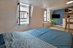 A bedroom with a bed, a desk, a chair, a TV, and a window. - Le Cocon des Remparts - Au coeur de l'intramuros (Saint-Malo)