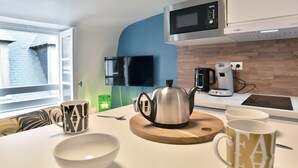 A modern kitchen with a microwave, kettle, and coffee maker on the counter. - Le Cocon des Remparts - Au coeur de l'intramuros (Saint-Malo)