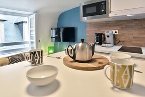 A modern kitchen with a microwave, kettle, and coffee maker on the counter. - Le Cocon des Remparts - Au coeur de l'intramuros (Saint-Malo)