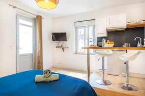 A room with a bed, a TV, a kitchenette, and a window. - Le Nid Choletais - Au centre-ville de Cholet (Cholet)