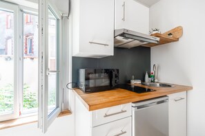 A compact kitchen with a microwave, sink, and wooden countertop. - Le Nid Choletais - Au centre-ville de Cholet (Cholet)