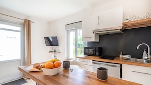 Moderni keittiö, jossa on puinen työtaso, mikroaaltouuni, pesuallas ja seinälle asennettu televisio.