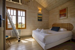Ein Zimmer mit Holzwänden, einem Bett, einer Leiter, einem Fenster und einem Poster an der Wand.