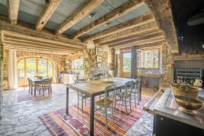Ein rustikaler Holzinnenraum mit einer Steinwand, einem Holzesstisch und einer Küchenzeile.