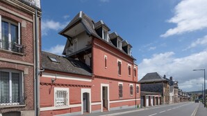 Un bâtiment en briques rouges doté d’un balcon, une rue devant et un ciel dégagé.