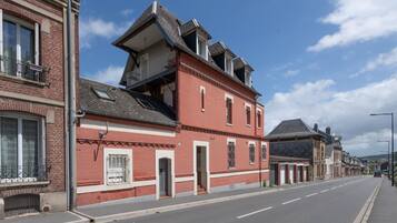 Un bâtiment en briques rouges doté d’un balcon, une rue devant et un ciel dégagé.