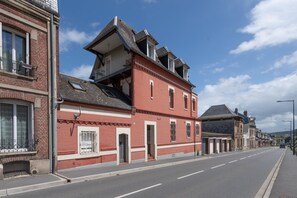 Un bâtiment en briques rouges doté d’un balcon, une rue devant et un ciel dégagé.