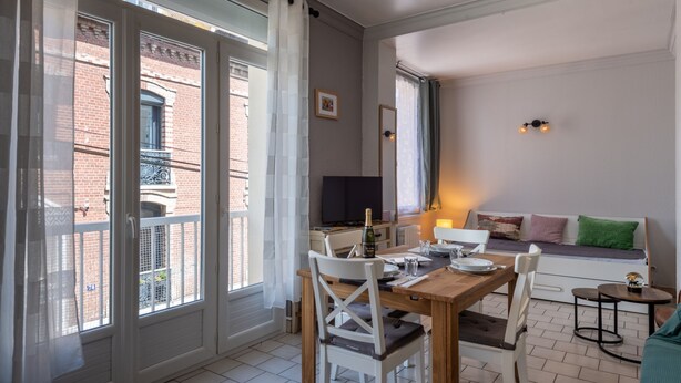 Un coin repas avec une table dressée pour deux personnes, un canapé et une petite table d’appoint.