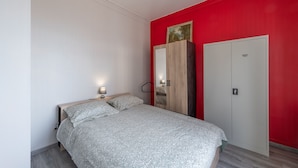 Une chambre à coucher avec un lit, une armoire et un mur d’accent de couleur rouge.