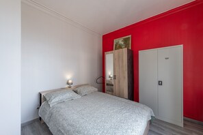 Une chambre à coucher avec un lit, une armoire et un mur d’accent de couleur rouge.