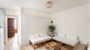A room with two wooden beds, a small wooden table, a potted plant, and a ceiling light fixture. - Bel Horizon Marin - Magnifique vue mer (Saint-Malo)