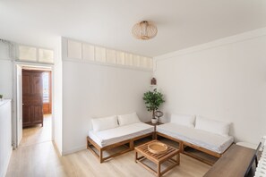 Ett rum med två sängar i trä, ett litet träbord, en krukväxt och en taklampa.