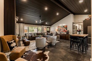 A spacious living area with a high ceiling, a dining area, and a kitchen. - Enjoy the Ride | Walk to Square | Bike Friendly (Bentonville)