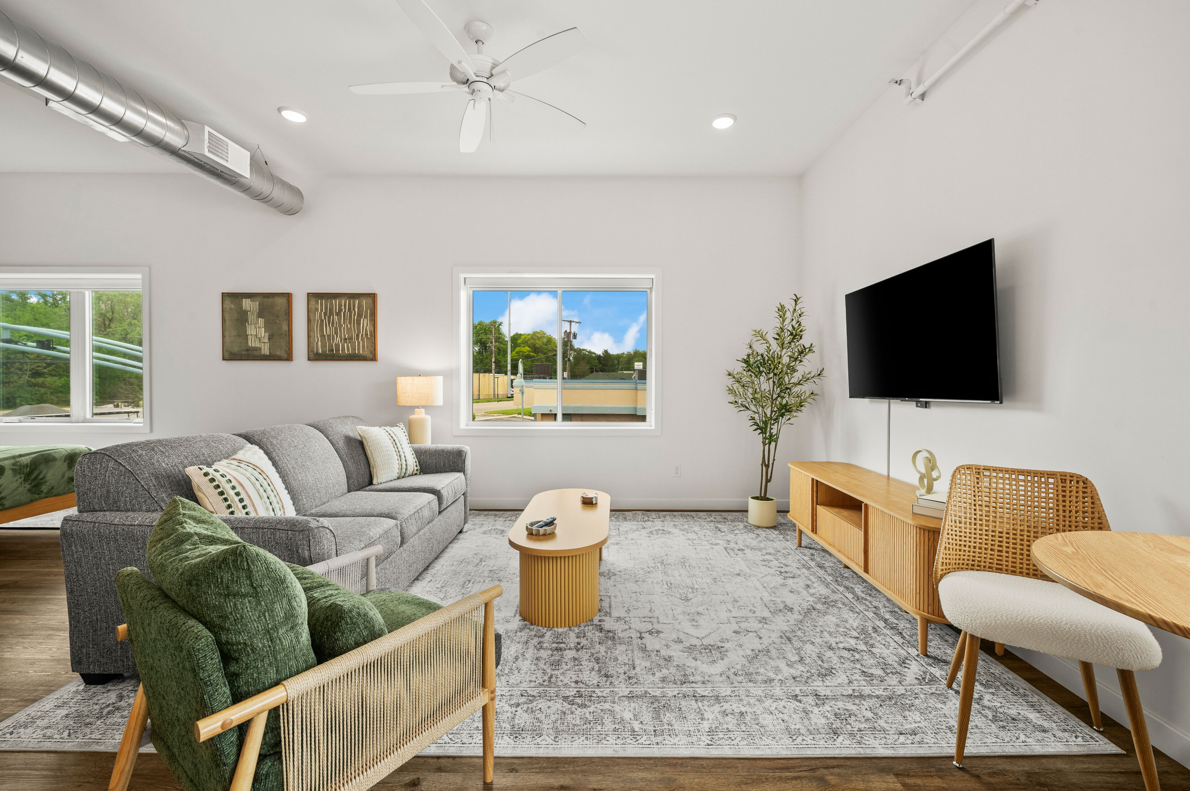 A modern living room with a sofa, coffee table, TV, and a view of the outdoors.