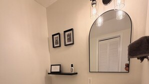 A bathroom with a toilet, sink, mirror, framed pictures, and a towel rack. - 3 Bedroom Home with Private Pool (Schertz)