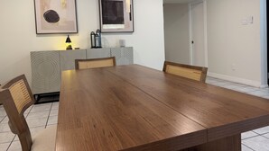 A dining area with a wooden table and chairs, framed artwork on the wall, and a modern light fixture. - 3 Bedroom Home with Private Pool (Schertz)