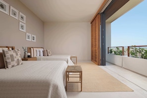 Ein Schlafzimmer mit zwei Betten, einem kleinen Hocker und einem Balkon mit Pflanzen.