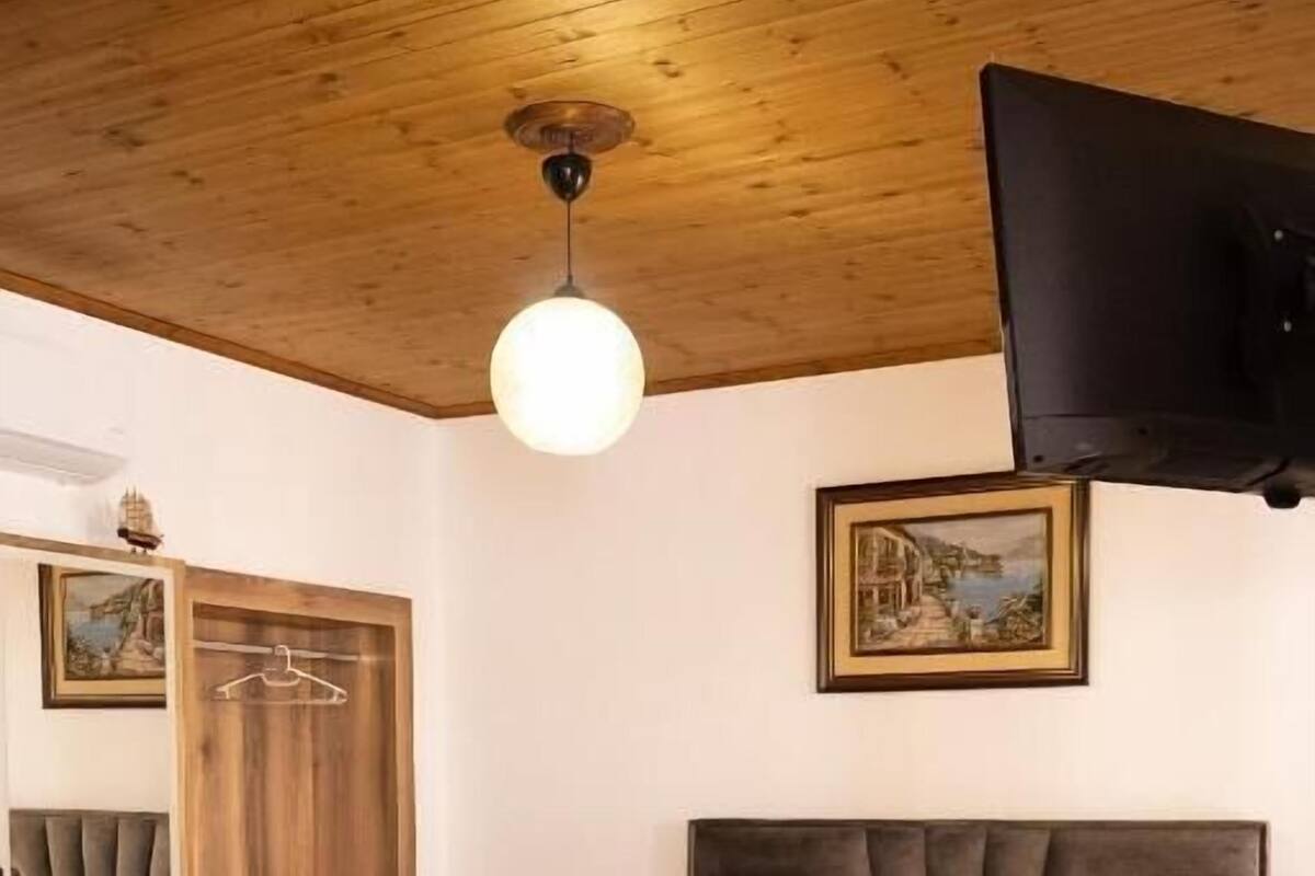 A room with a bed, a table, chairs, a TV, and a painting on the wall.