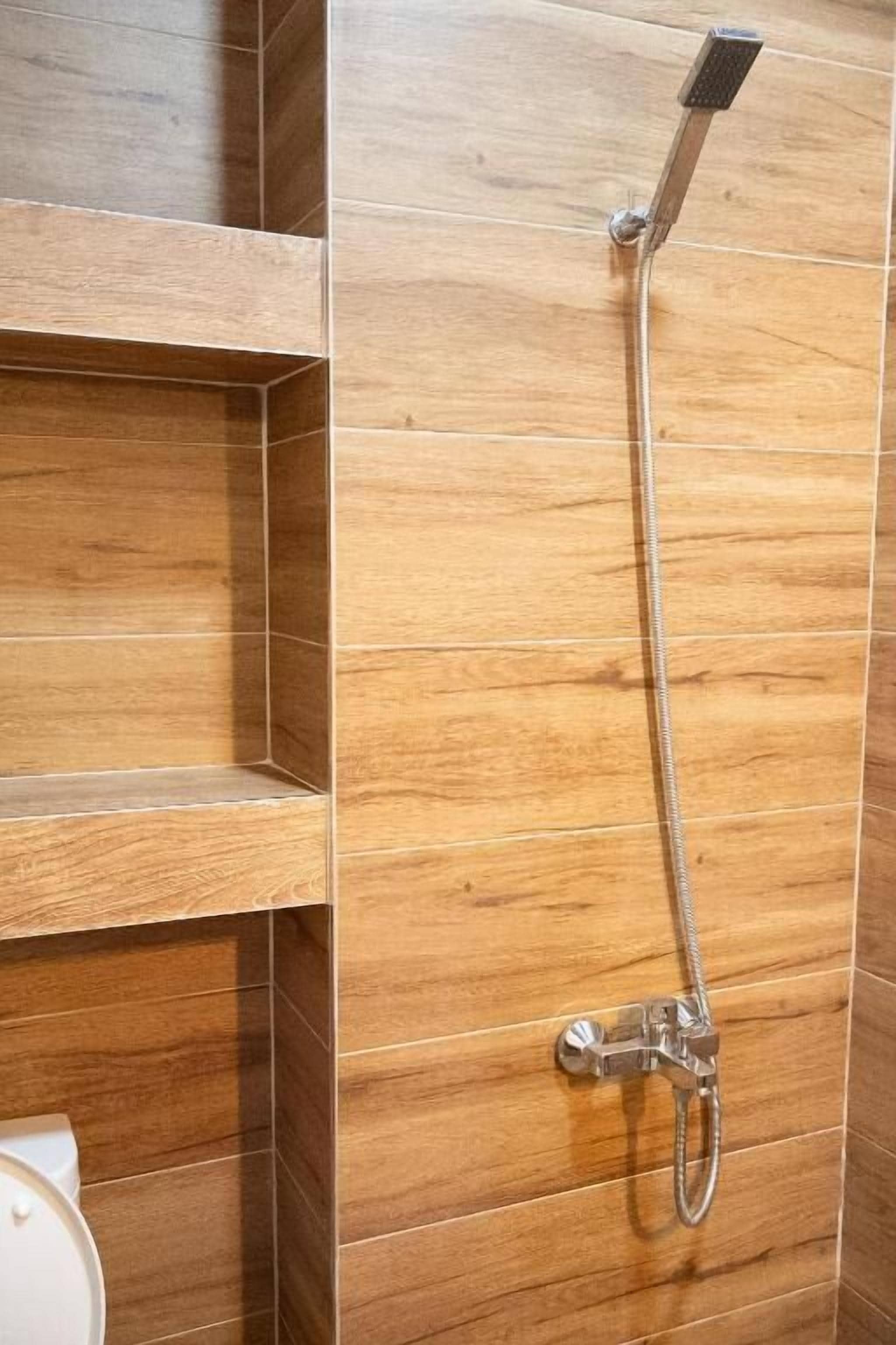 A shower with a handheld showerhead and a wall-mounted faucet.