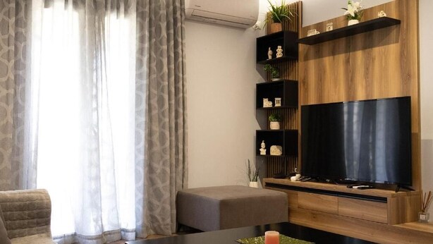 Una sala de estar moderna con una televisión de pantalla plana, estanterías de madera y un sofá gris.