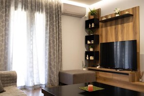 Uma sala de estar moderna com televisão de tela plana, prateleiras de madeira e um sofá cinza.