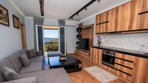 Una sala de estar moderna con sofá, mesa de centro y una cocina con armarios de madera y salpicadero de mármol.