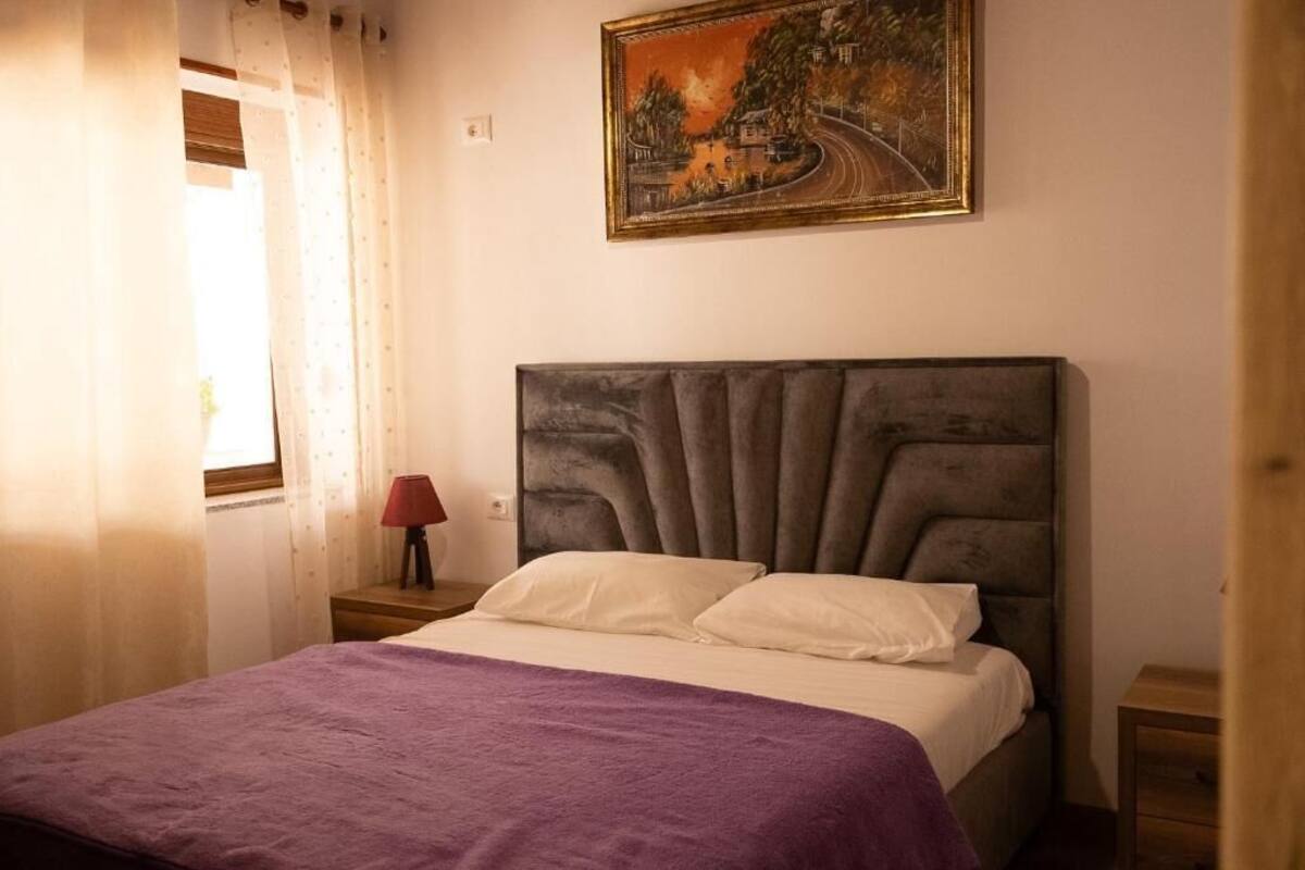 A bedroom with a bed, a nightstand, a lamp, and a painting on the wall.