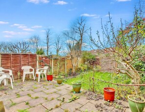 A backyard with a wooden fence, potted plants, and outdoor furniture. - Cosy garden flat in Finchley, North London - Pass the Keys (London)