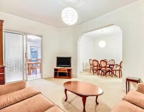 A living room with a sofa, a coffee table, a TV, and a dining area with chairs and a table. - Cosy garden flat in Finchley, North London - Pass the Keys (London)