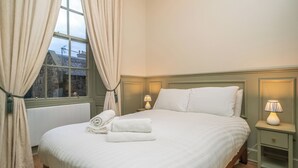 A neatly made bed with white linens, a window with curtains, and two bedside lamps. - Charming Georgian flat in the Heart of Edinburgh - Pass the Keys (Edinburgh)