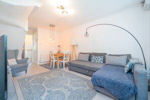 A modern living room with a sofa, armchairs, a dining table, and a patterned rug. - Quiet St. Albans Cottage with Free Parking - Pass the Keys (St Albans)