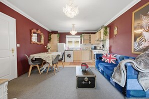 Ein kompakter Wohnbereich mit Essbereich, Küche und einer Couch mit Union-Jack-Kissen.