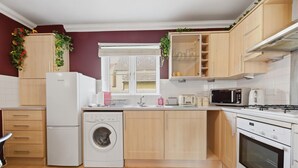 A modern kitchen with a washing machine, microwave, and oven.