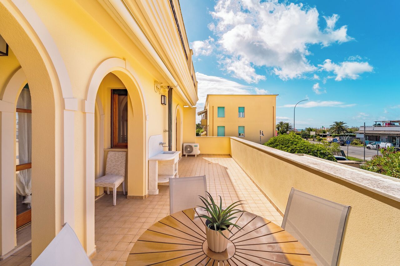 A balcony with a table, chairs, and a potted plant.