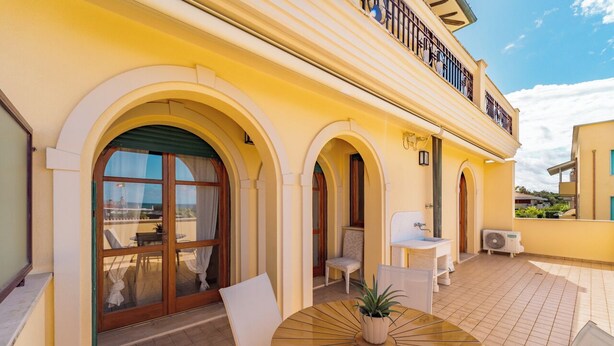 A hotel with a patio area featuring a round table, chairs, and a potted plant. - Villa Sorrento - Two Bedroom Apartment, Sleeps 4 (Marina di Massa)