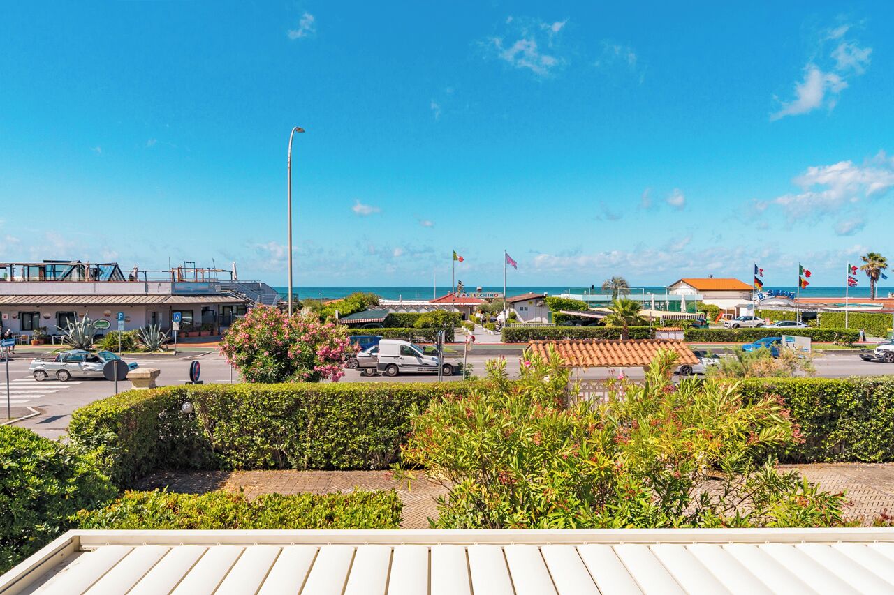 A coastal view with a road, buildings, and flags.
