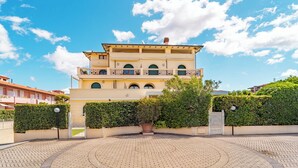 A multi-story building with a central courtyard, balconies, and a clear sky. - Villa Sorrento - Two Bedroom Apartment, Sleeps 4 (Marina di Massa)