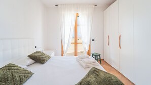 A bedroom with a bed, a nightstand, a green stool, and a wardrobe. - Villa Sorrento - Two Bedroom Apartment, Sleeps 4 (Marina di Massa)