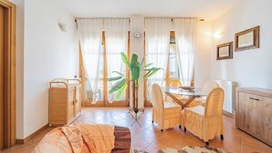 A room with a dining table, chairs, a cabinet, a plant, and a sofa. - Villa Sorrento - Two Bedroom Apartment, Sleeps 4 (Marina di Massa)