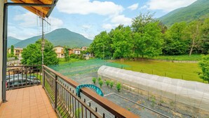 A balcony with a view of a greenhouse, a mountain, and a residential area. - All'antico Peso - Two Bedroom Apartment, Sleeps 5 (Festiona)