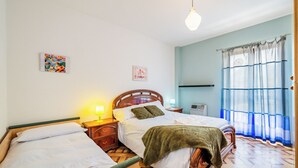 A bedroom with two beds, a wooden headboard, a nightstand with a lamp, a wall-mounted shelf, and a window with curtains. - All'antico Peso - Two Bedroom Apartment, Sleeps 5 (Festiona)