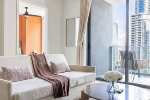 A modern living room with a sofa, a coffee table with a vase, and a view of a high-rise building. - Vibrant City Retreat with Balcony and Pool in Miami G3413 (Miami)