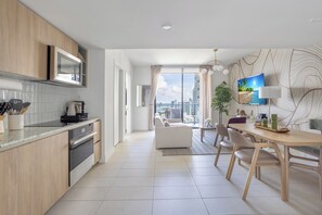 A modern kitchen with a microwave, stove, and cabinets. There is a dining area with a table and chairs. - Vibrant City Retreat with Balcony and Pool in Miami G3413 (Miami)