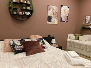 Une chambre à coucher comprenant un lit, une table de chevet, une commode et des œuvres d’art murales.