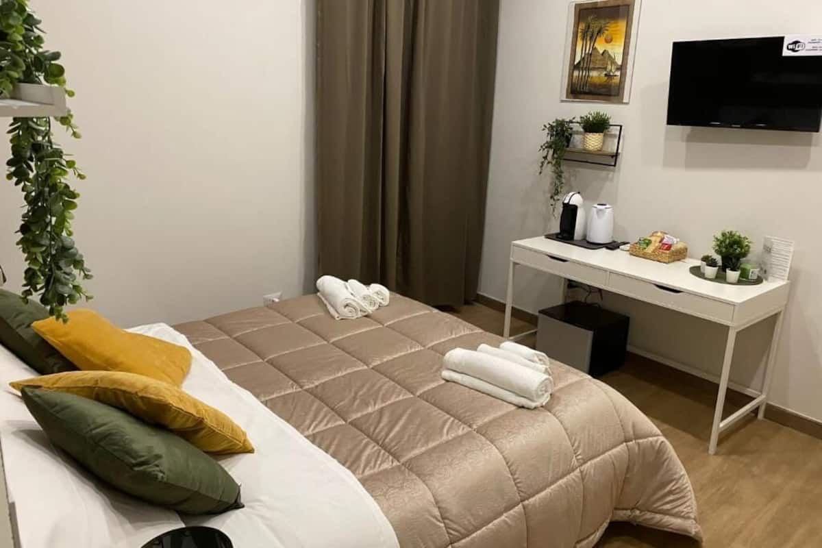 A hotel room with a bed, a desk, a TV, and a window with curtains.