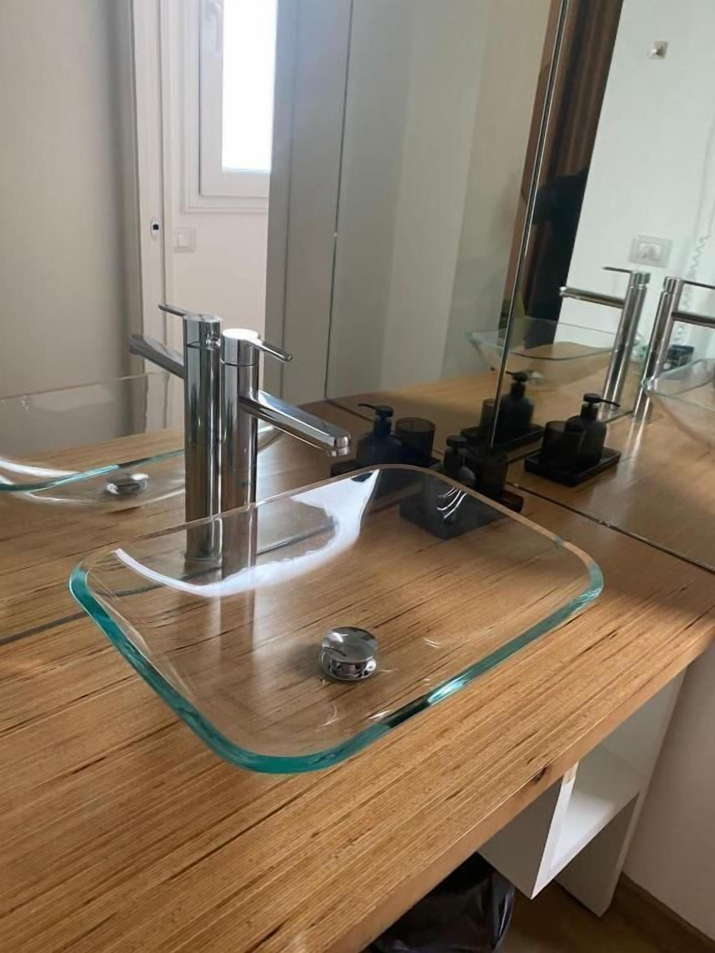 Une salle de bain avec un lavabo en verre, un robinet chromé et un miroir.